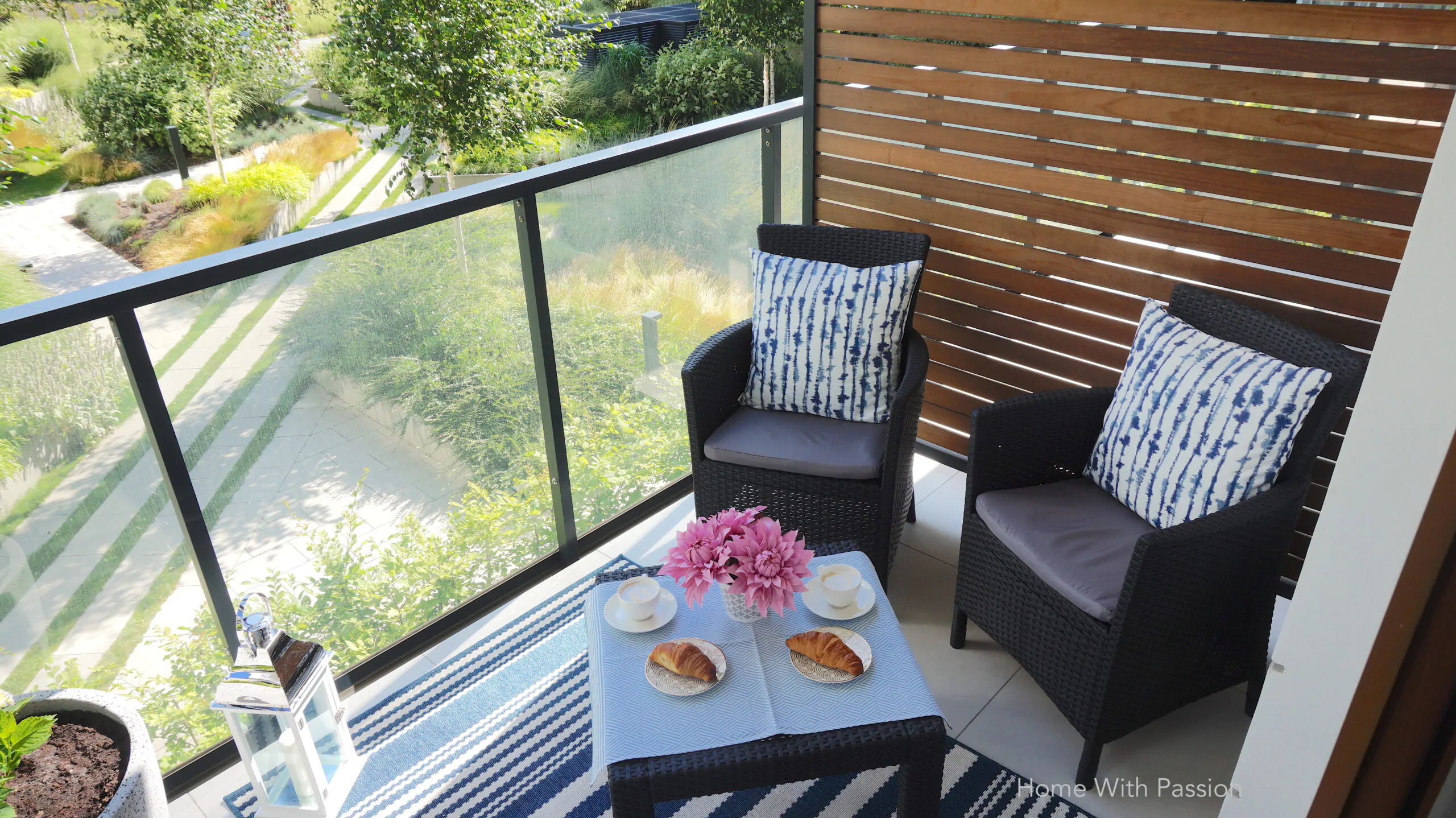 Balkon z widokiem na zieleń, meble rattanowe, stolik z croissantami i kawą