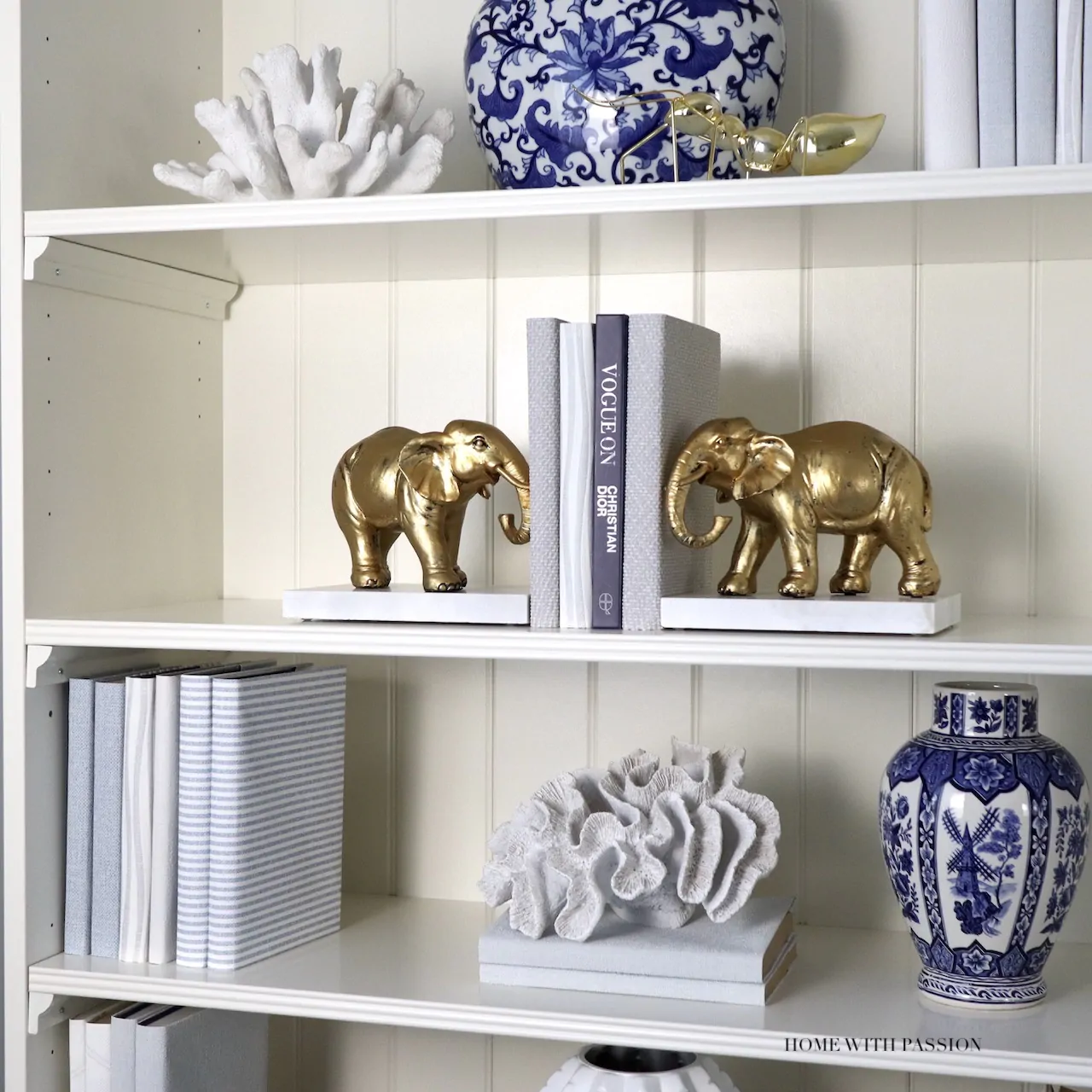 Dekoracje na półce w domowym biurze – złote figurki słoni, książki i porcelanowy wazon
