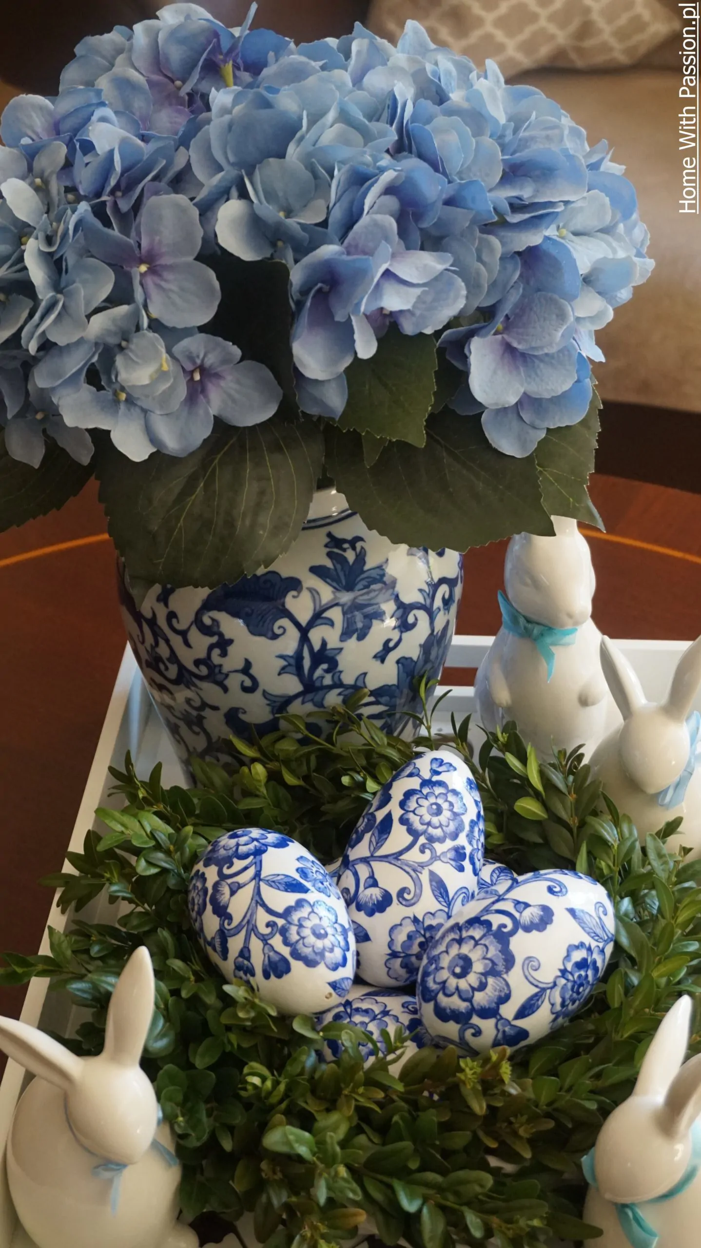 Elegancka dekoracja wielkanocna w stylu hampton – jajka z niebieskim wzorem, hortensja i ceramiczne króliki na tacy