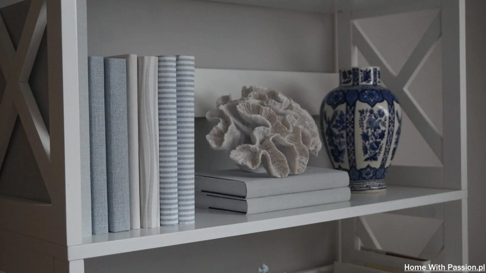 Półka w stylu Hampton z książkami, dekoracyjnym koralowcem i ceramicznym wazonem