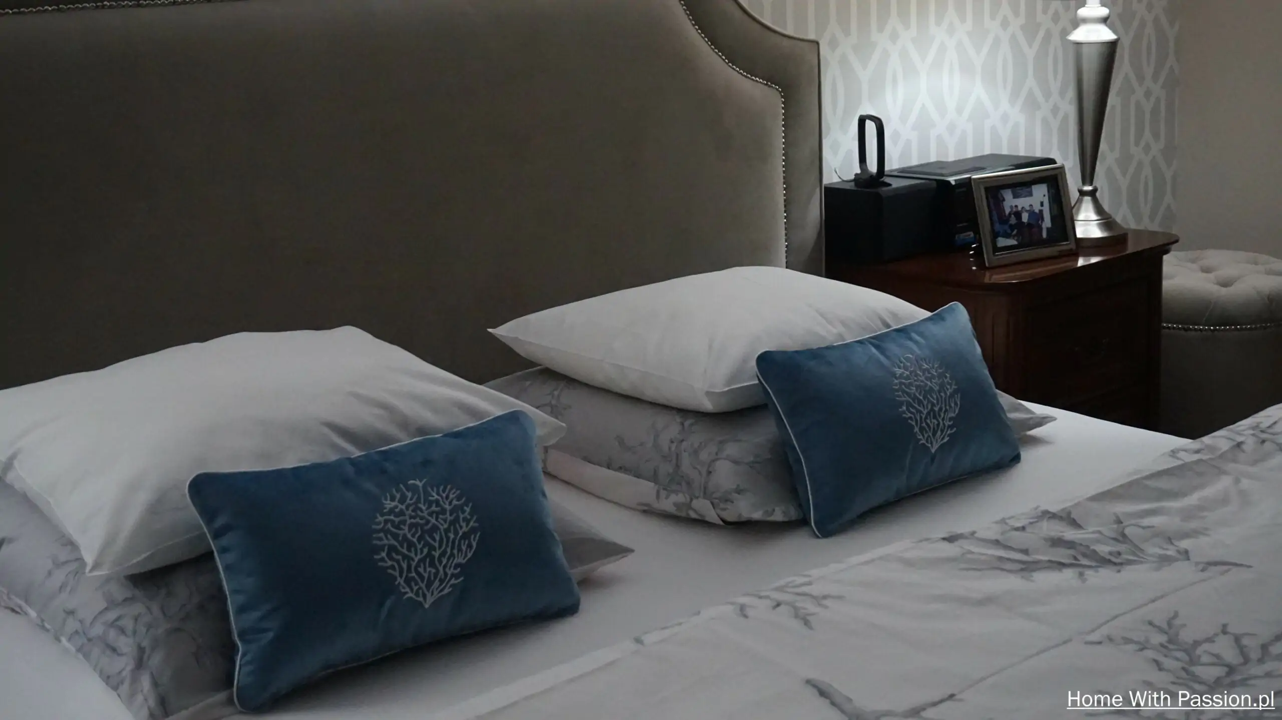 elegancka aranżacja łóżka w sypialni poduszki dekoracyjne w kolorze niebieskim i tapicerowany zagłówek