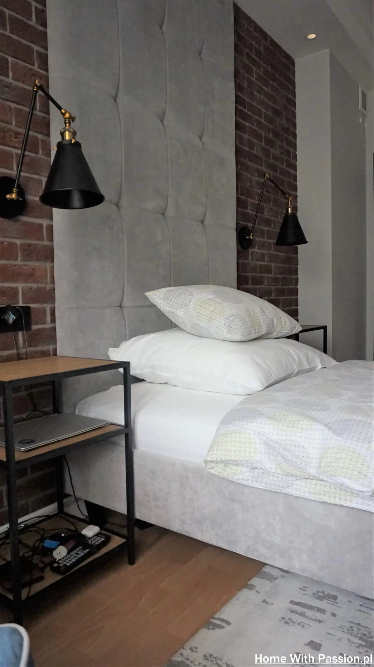 Łóżko tapicerowane loft z kinkietami i stolikiem nocnym przy ceglanej ścianie