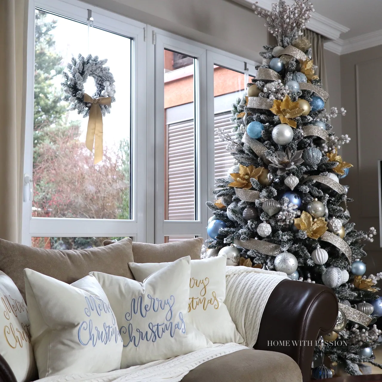 Przytulny salon z ozdobioną choinką w kolorach złota i srebra oraz jasną sofą z poduszkami Merry Christmas