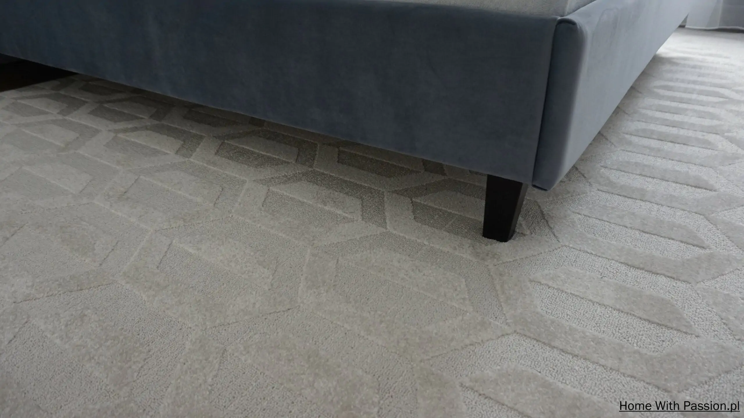 Dywan w jasnym kolorze z geometrycznym wzorem pod łóżkiem, elegancka aranżacja podłogi w sypialni
