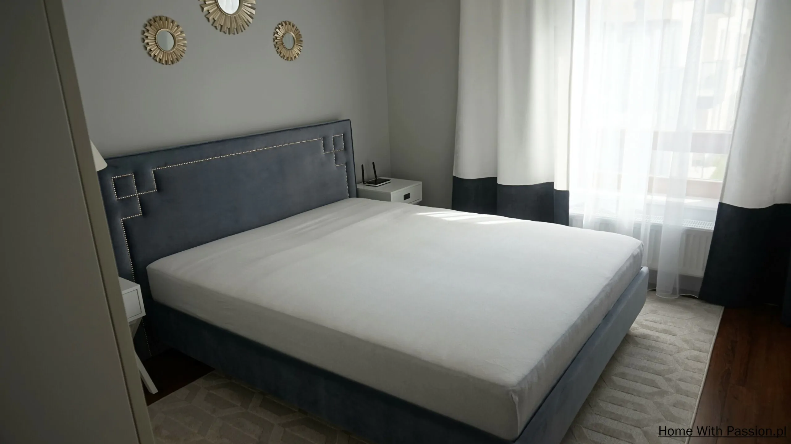 Łóżko z miękkim, niebieskim zagłówkiem w eleganckiej sypialni hampton