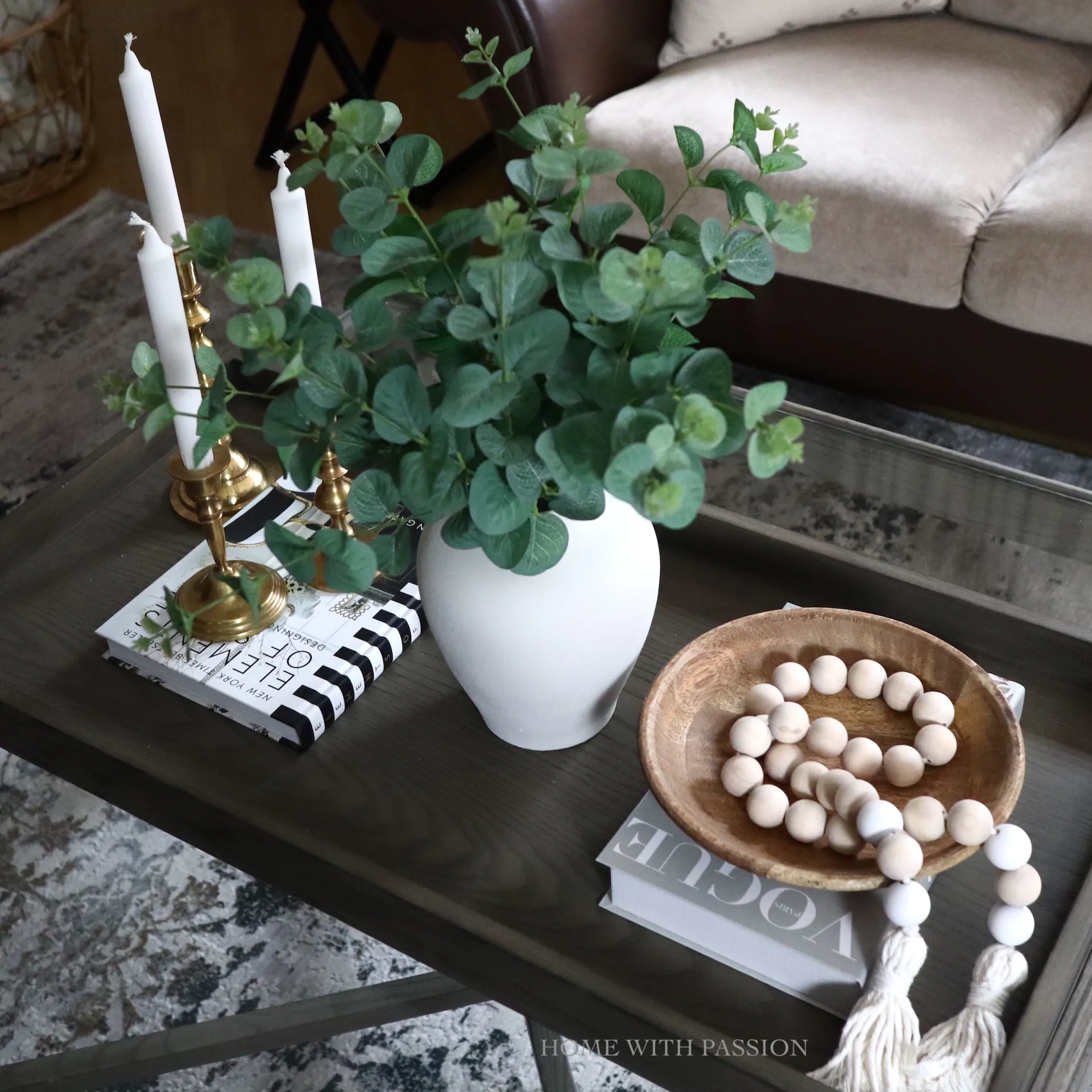 Minimalistyczna aranżacja stolika kawowego z eukaliptusem, świecami i drewnianą misą – naturalny styl salonu