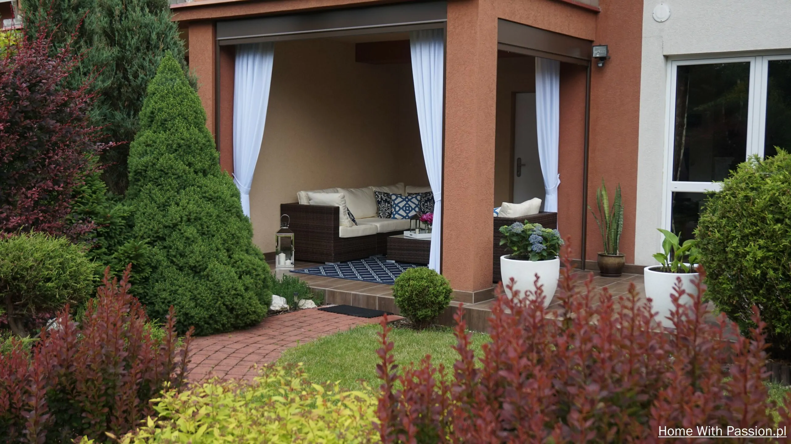 Aranżacja tarasu w stylu Hampton w ogrodzie z roślinnością i ścieżką z kostki