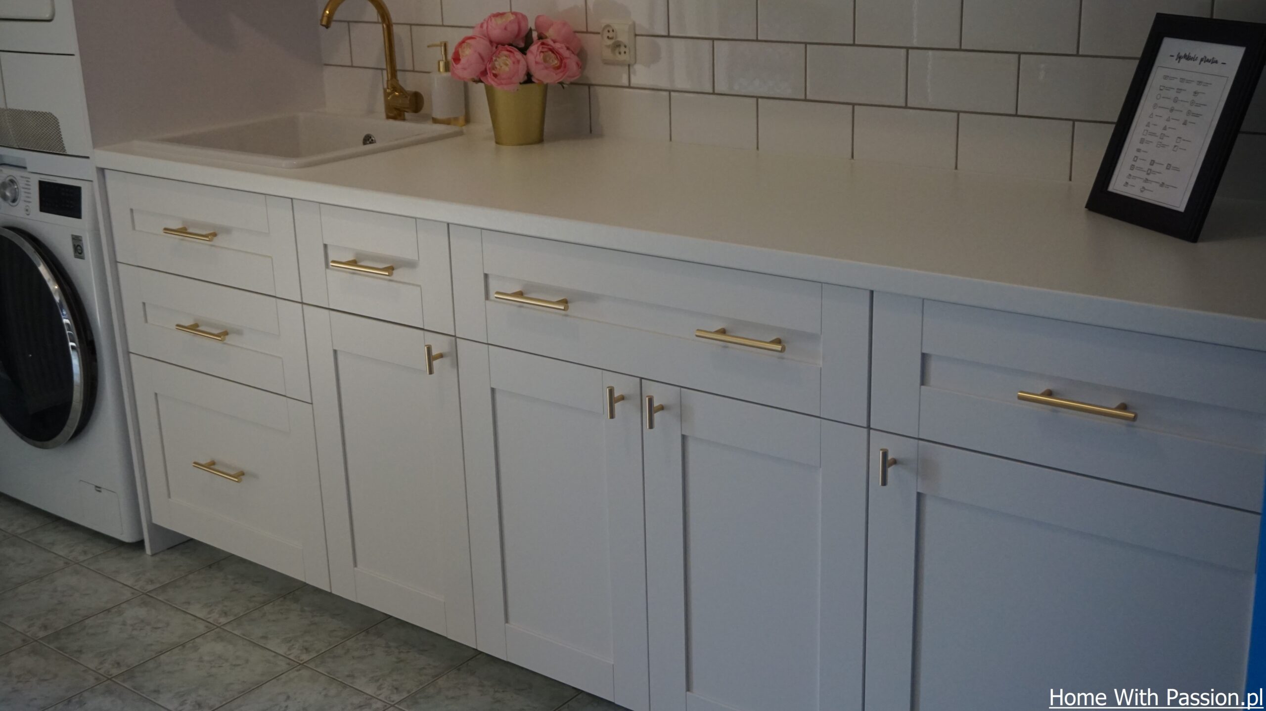 białe szafki ze złotymi uchwytami w domowej pralni
